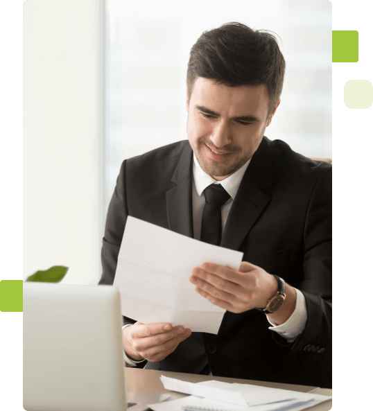 Homem branco vestido terno segurando uma folha de papel